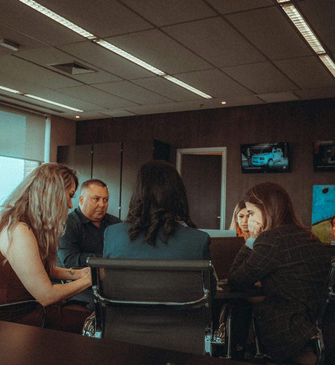 Small editorial team reviewing printed pages around a table