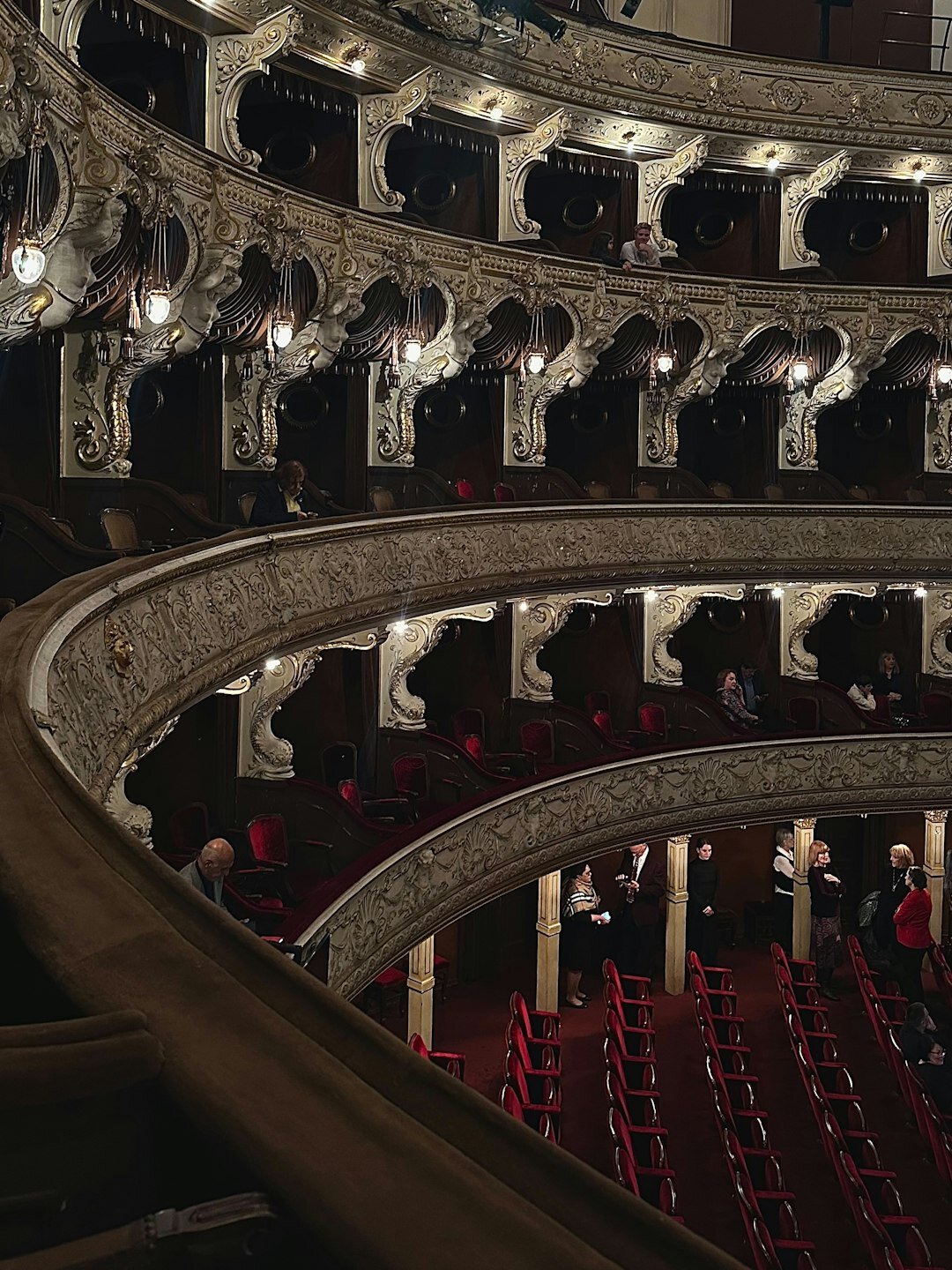 Grand theatre interior with gilded balconies and red velvet seats at dusk