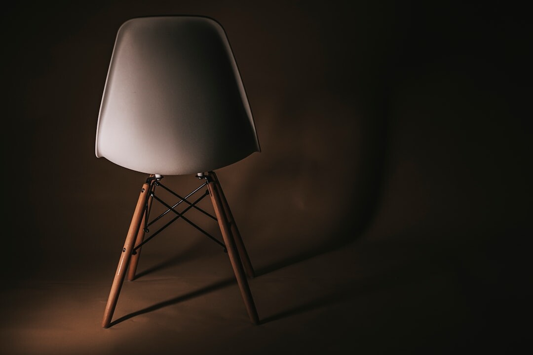 Still life of a designer chair and brass lamp in a minimalist studio
